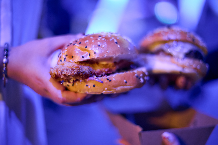 Hands holding beef burgers.